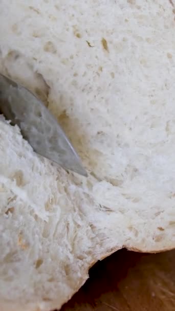 Цілий зерновий хліб покласти на кухонну дерев'яну тарілку з шеф-кухарем, який тримає золотий ніж для різання. Свіжий хліб на столі крупним планом. Свіжий хліб на кухонному столі Здорове харчування та традиційна концепція пекарні - Кадри, відео