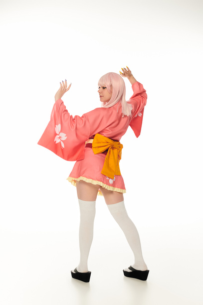 mujer joven estilo anime en kimono rosa con lazo amarillo y calcetines blancos de rodilla en blanco, longitud completa - Foto, imagen