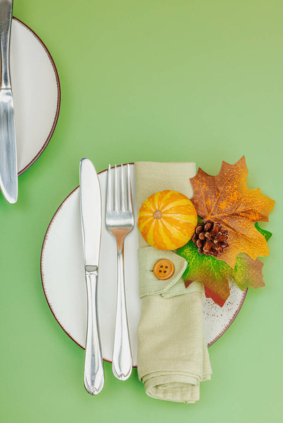 秋のテーブルの設定。 感謝祭のカトラリー,伝統的な秋の装飾,平らな層. お祝いの居心地の良い気分,カボチャ,葉,サバンナグリーンの背景,トップビュー - 写真・画像