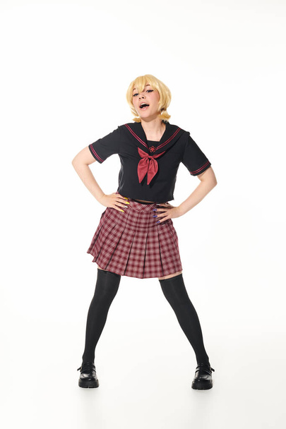 concepto cosplay, mujer en peluca rubia amarilla y uniforme escolar posando con las manos en las caderas en blanco - Foto, imagen