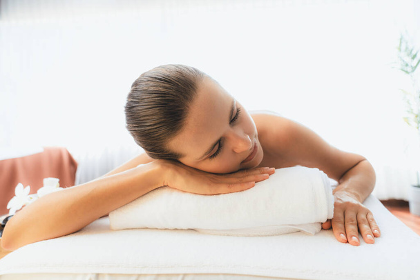 Blanke vrouw klant genieten van ontspannende anti-stress spa massage en verwennerij met schoonheid huid recreatie vrijetijdsbesteding in daglicht ambient salon spa in luxe resort of hotel. Stil maar. - Foto, afbeelding