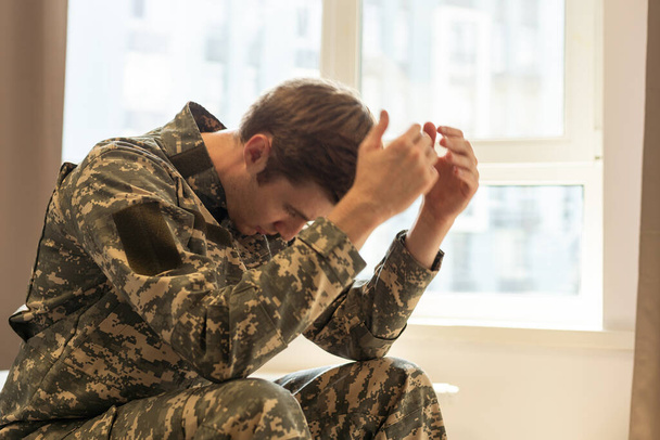 治療セッション中にカメラを思慮深く見て中年悲しい、絶望的な軍人の肖像画。うつ病の精神的外傷に苦しむ障害のある兵士。PTSDの概念。水平射撃. - 写真・画像