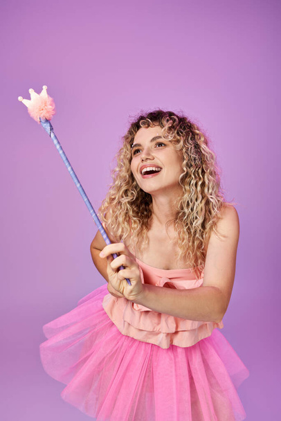 hermosa mujer en vestido rosa hechizo de lanzamiento con varita mágica y mirando hacia otro lado, concepto de hada diente - Foto, imagen