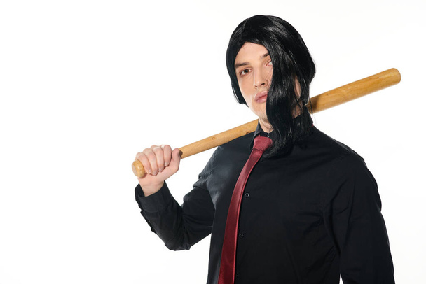 jovem de peruca preta e gravata vermelha segurando bastão de beisebol e olhando para a câmera no branco, cosplayer - Foto, Imagem
