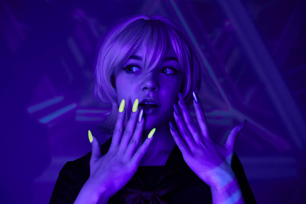 donna bionda stupita con manicure fluorescente in luce blu al neon su sfondo astratto, stile anime - Foto, immagini