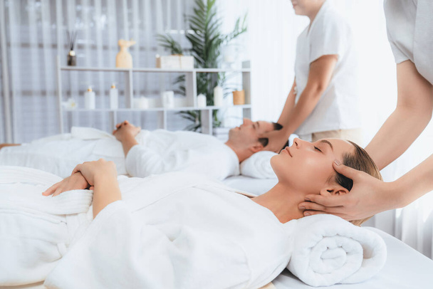 Caucasian couple enjoying relaxing anti-stress head massage and pampering facial beauty skin recreation leisure in dayspa modern light ambient at luxury resort or hotel spa salon. Quiescent - Photo, Image