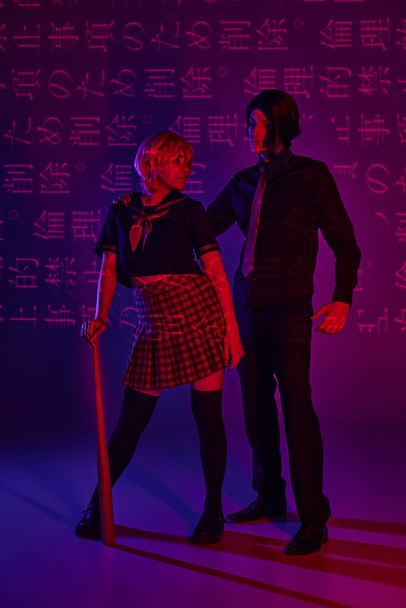 anime woman with baseball bat looking at boyfriend on neon purple backdrop with hieroglyphs - Photo, Image