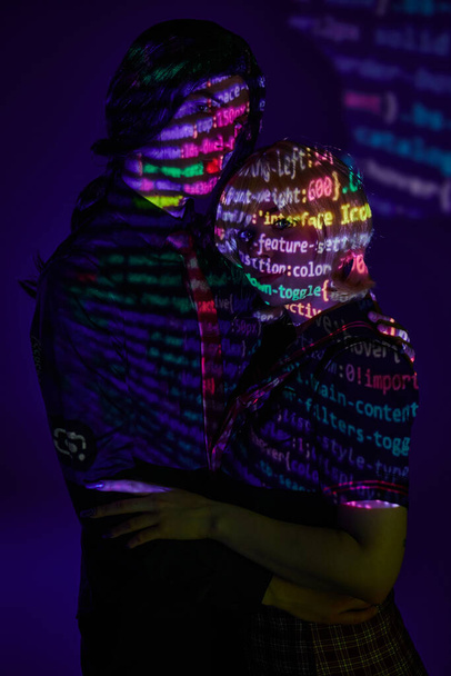 pareja moderna en coloridos símbolos de programación de neón proyección sobre fondo azul, concepto de cosplay - Foto, Imagen