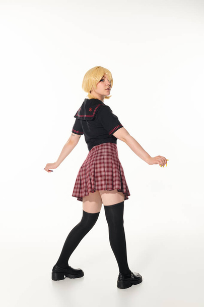 volledige lengte van jonge anime vrouw in school uniform en geel blonde pruik op wit, jeugd cultuur - Foto, afbeelding