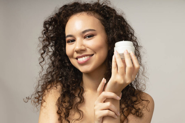 Aantrekkelijk meisje brengt crème op haar gezicht - Foto, afbeelding