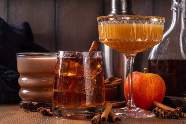 Maple syrup autumn cocktails. Boozy strong alcohol, non-alcoholic mocktail drinks with apple cider, liqueur and spices, on dark wooden background copy space - Photo, Image