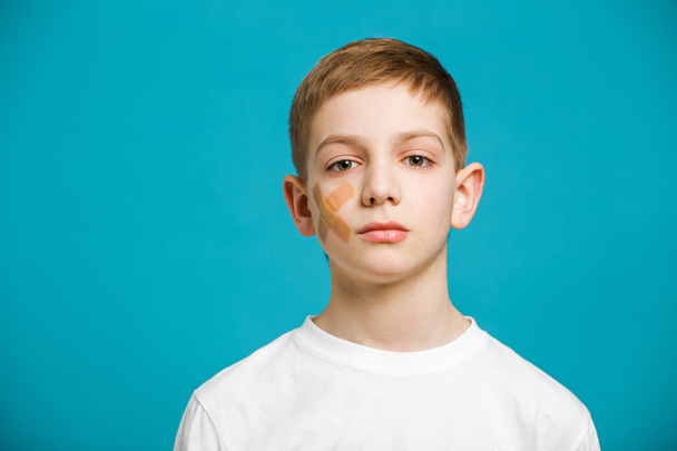 Portrait of a boy with adhesive plaster on his cheek - Foto, afbeelding