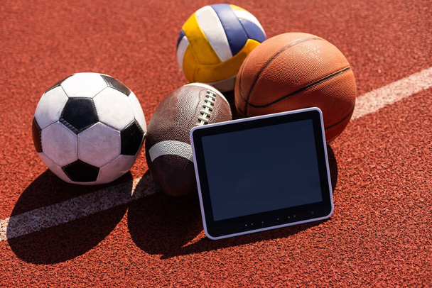 Tablet ordenador y pelotas. Concepto de apuesta deportiva. - Foto, Imagen