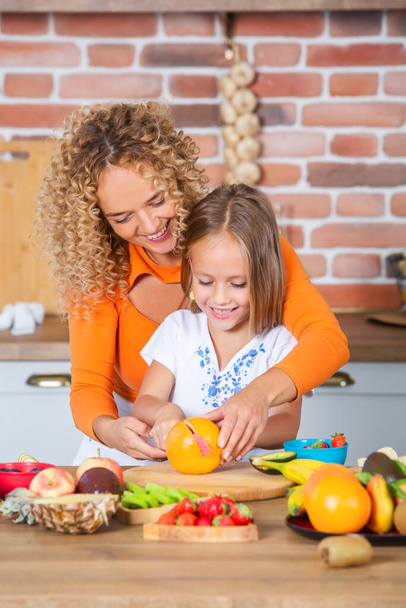 Мать и дочери готовят вместе на кухне. Концепция здорового питания. Портрет счастливой семьи со свежими смузи. - Фото, изображение