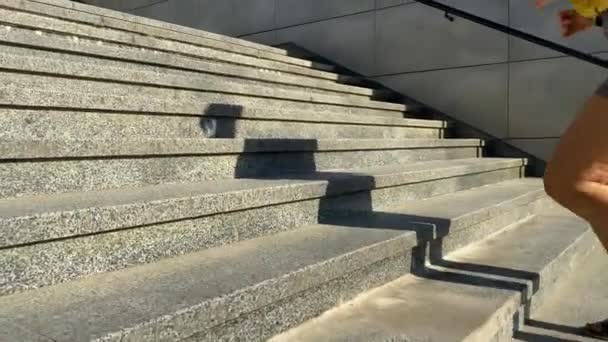Eine junge Frau mit niedrigem Schnitt läuft am Morgen die Treppe im öffentlichen Park hinauf, in der Morgensonne, und Schatten werfen sich auf die Stufen. Energiegeladener Start in den Tag, täglicher Trainingsablauf - Filmmaterial, Video