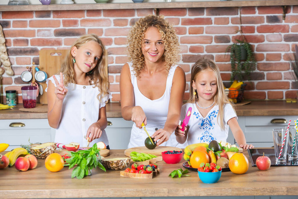 Мати і доньки готують разом на кухні. Концепція здорової їжі. Портрет щасливої сім'ї зі свіжими смузі. - Фото, зображення