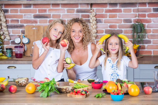 Μητέρα και κόρες μαγειρεύουν μαζί στην κουζίνα. Υγιεινή διατροφή. Πορτρέτο της ευτυχισμένης οικογένειας με φρέσκα smoothies. - Φωτογραφία, εικόνα