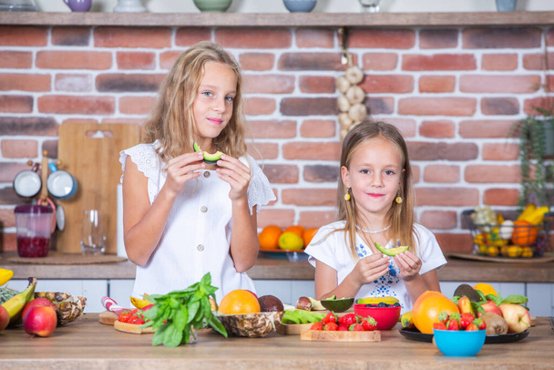 Két kislány a konyhában friss zöldségekkel. Egészséges étel koncepció. Boldog nővérek.. - Fotó, kép