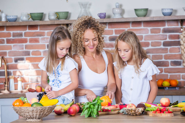 Mère et filles cuisinent ensemble dans la cuisine. Concept d'alimentation saine. Portrait de famille heureuse avec des smoothies frais. - Photo, image