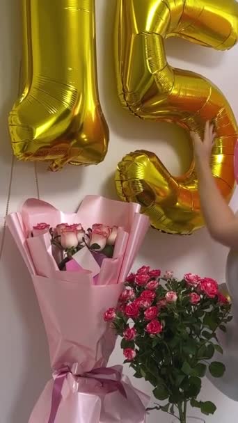 dospívající dívka slaví narozeniny 15. výročí balónky květiny čísla na bílé zdi focení na video pro sociální sítě na internetu dovolená zdobí dekorace pokojů. džíny - Záběry, video