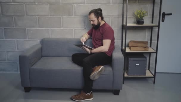jonge zakenman met behulp van tablet pc op de bank in modern kantoor - Video
