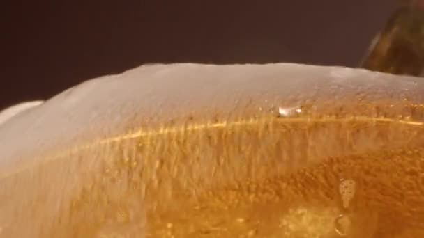 Низкий угол закрытия стекла, наполненный холодным золотым пивом с переполненной пеной и шипящими пузырями - Кадры, видео