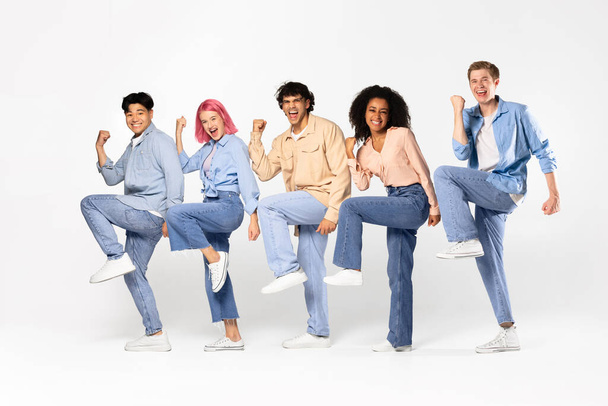 Yes. Overjoyed multiracial teen friends cheering and shaking clenched fists, celebrating win and good news standing isolated over white studio background, full length - Фото, зображення