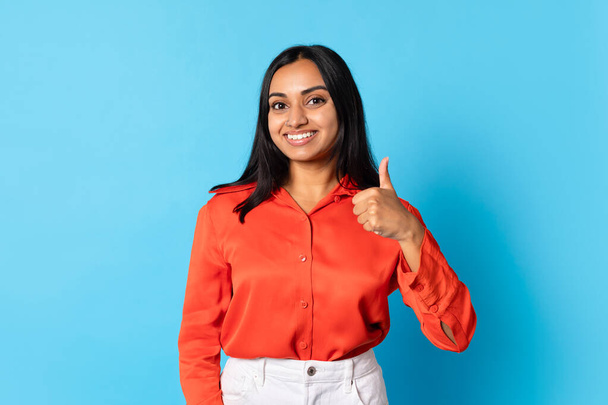 I Like It. Smiling Young Indian Woman Gesturing Thumbs Up In Approval, Standing Over Blue Studio Background. Customer Lady Showing Like Gesture Posing In Casual Clothes, Looking At Camera - Photo, Image