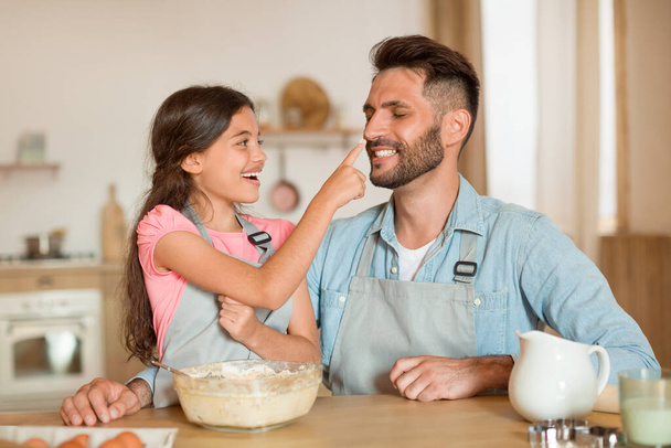 Возбужденные отец и дочь сближаются во время приготовления пищи и выпечки вместе на кухне, папа и девочка-подросток пекут тесто и веселятся - Фото, изображение