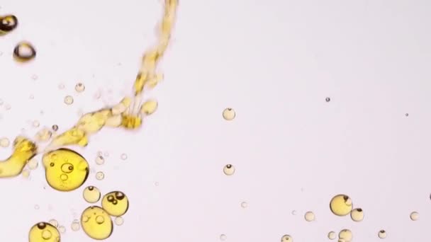 Крупный план замедленного движения желтого масла, выливающегося в прозрачную воду и образующего множество плавающих пузырьков для абстрактного фона - Кадры, видео
