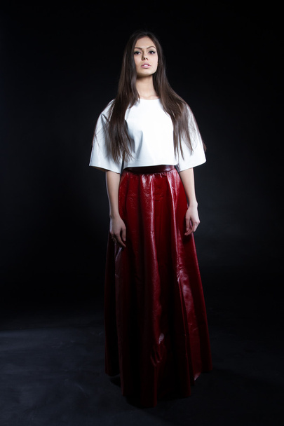 Girl in a red long skirt on a black background - 写真・画像