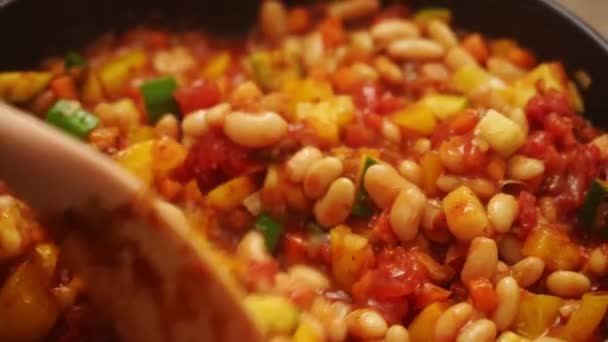 D'en haut de cuisson méconnaissable en remuant les haricots blancs dans une casserole avec cuisson des légumes et de la tomate cause tout en préparant le gratin dans la cuisine - Séquence, vidéo