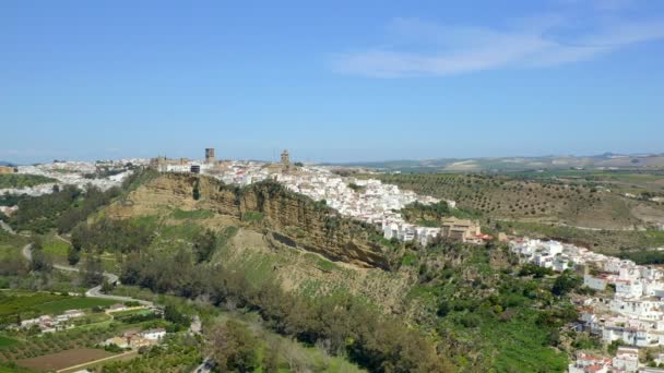 Panorama izquierda vista del dron de campos verdes ubicados cerca del acantilado con la ciudad de Arcos de la Frontera contra el cielo azul nublado durante el día en Andalucía, España - Imágenes, Vídeo