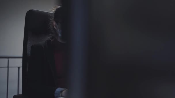 жінка в масці для обличчя за допомогою комп'ютера в офісі - Кадри, відео