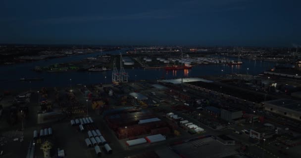 Вид на повітряний дрон нічного порту Амстердама, зосереджений на логістичних компаніях, судноплавній промисловості та перевезенні товарів над водою в сутінках. Нідерланди. - Кадри, відео