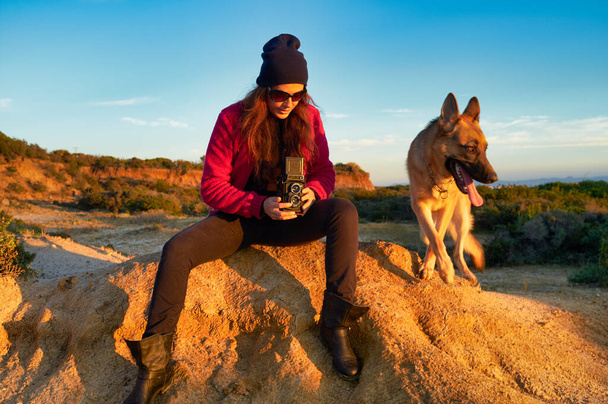 Kobieta fotograf przechwytuje psa z 6x6 rocznika aparat fotograficzny w krajobrazie z czystym niebem. Z Kopiuj przestrzeń - Zdjęcie, obraz