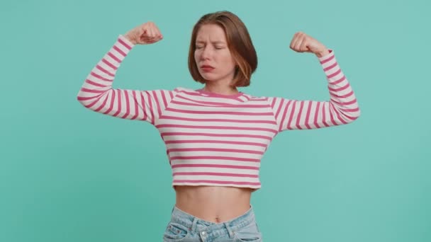 I am strong and independent. Young woman showing biceps and looking confident, feeling power strength to fight for rights, energy to gain success win. Girl isolated alone on blue studio background - Footage, Video
