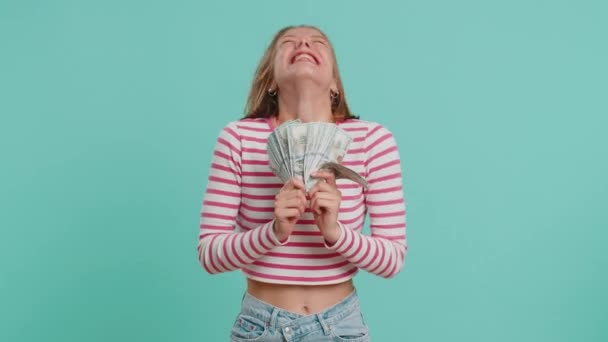 Богатая, довольная молодая женщина, размахивает деньгами, долларом, банкнотами, веером, успешной бизнес-карьерой, победителем лотереи, большим доходом, богатством. Девушка в кукурузнике изолирована на голубом фоне, в помещении - Кадры, видео