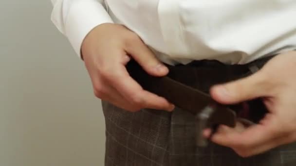 The man fastens the belt on his pants. Stylish men's accessory. - Footage, Video