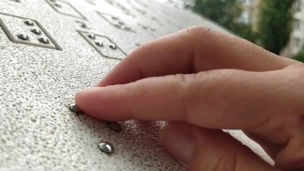 Ένα χέρι είναι απτική ανάγνωση Braille σε εξωτερικούς χώρους σε tablet σε ένα δημόσιο πάρκο. Παγκόσμια ημέρα οράσεως. Παγκόσμια Ημέρα Μπράιγ. Έννοια της Ημέρας των Τυφλών και Ανήμπορων - Πλάνα, βίντεο