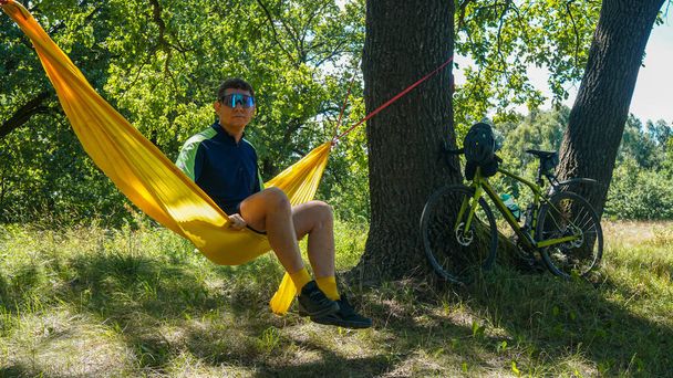 cyklista spočívá na houpací síti, žluté houpací síti a otevřeném vzduchu - Fotografie, Obrázek