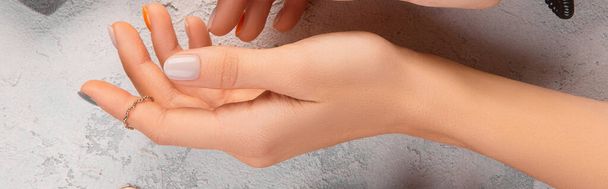 Kobiece ręce z modnym minimalnym manicure na szarym tle. Letni wiosenny projekt paznokci. Szablon dla mediów społecznościowych - Zdjęcie, obraz
