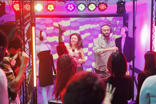 ナイトクラブのエレクトロニックミュージックフェスティバルで演奏したり歌ったりする男女ミュージシャン. クラブでダンスフロアで踊っているシンガーとDJテクノバンド - 写真・画像