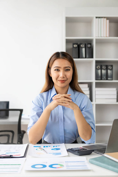 自宅で金融文書をチェックするアジアの女性会計士は,オンラインで税金を支払う前に計算機を使用する必要があります. ビジネス予算プランニング垂直画像 - 写真・画像