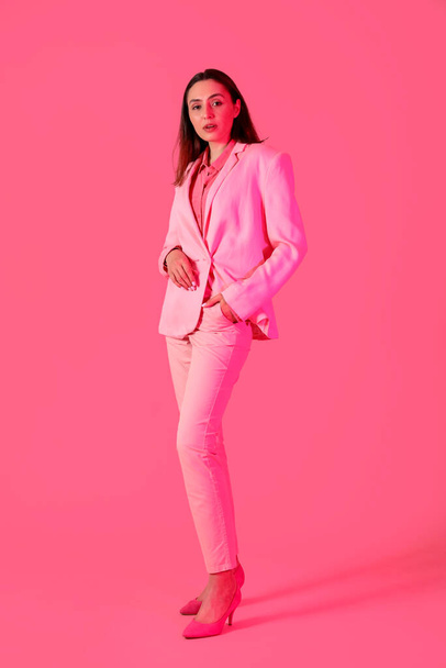 Junge Frau im eleganten Anzug auf rosa Hintergrund - Foto, Bild