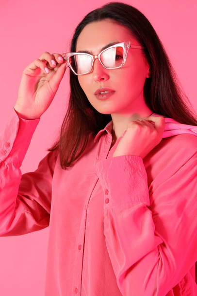 Mujer joven en gafas de sol con estilo sobre fondo rosa, primer plano - Foto, imagen