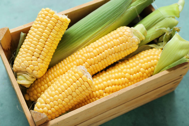Fa doboz friss kukorica cobs a zöld asztalon - Fotó, kép