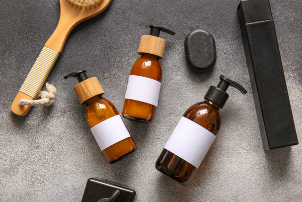 Bottiglie di shampoo, pietra spa e pennello su sfondo grigio - Foto, immagini