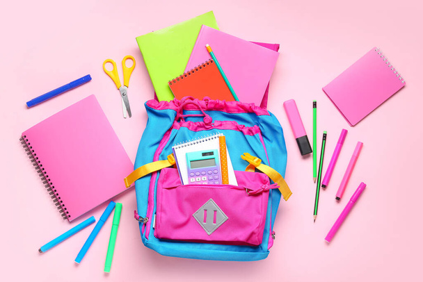 Elegante mochila escolar con diferentes artículos de papelería sobre fondo rosa - Foto, Imagen