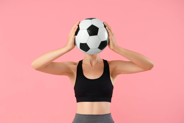 Bela jovem mulher esportiva com bola de futebol no fundo rosa - Foto, Imagem
